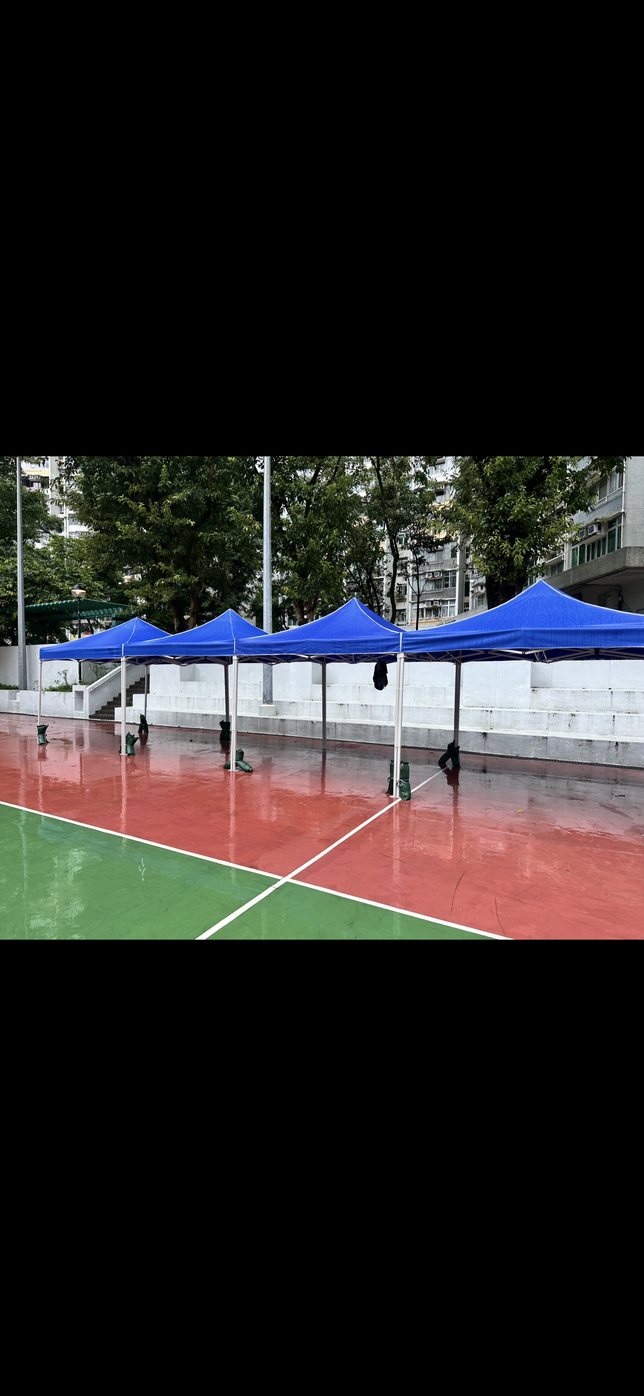 Blue rental tents set up on a sports court — actual site photo